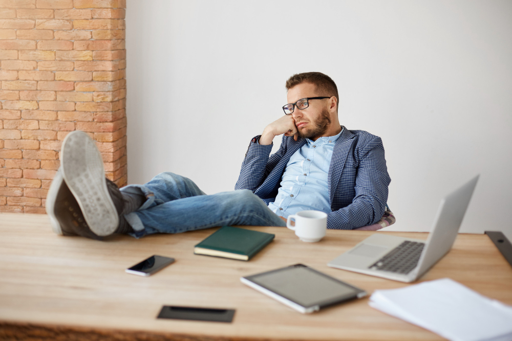 A person with the legs on the desk looking unhappily into the distance.
