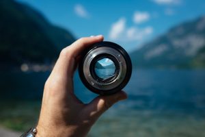 Someone holding a camera objective. everything is blurry, except what is in focus.