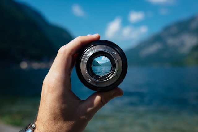 Someone holding a camera objective. everything is blurry, except what is in focus.